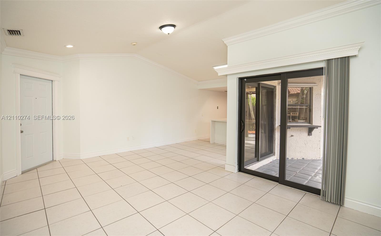 Vaulted ceilings, neutral tile flooring, sliding glass patio doors, crown molding, and recessed lighting