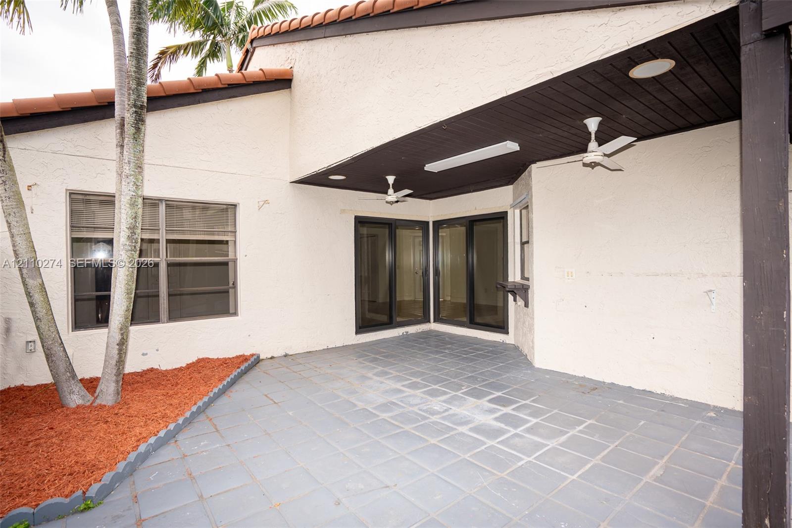 Covered outdoor patio featuring tiled flooring, recessed lighting, dual ceiling fans, and sliding glass doors