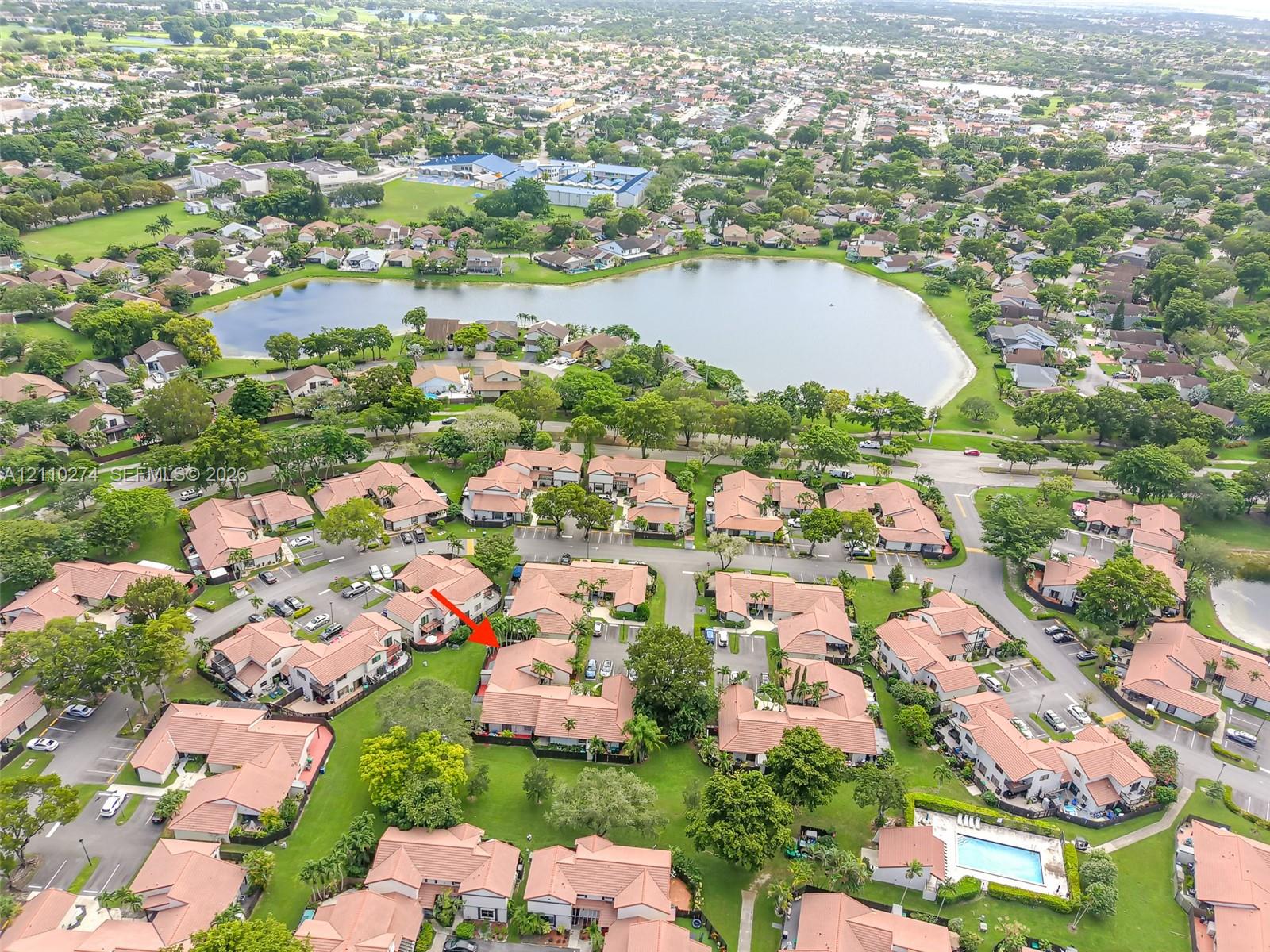 Aerial perspective of a multi-unit residential property featuring tile roofing, stucco exterior finishes, and established landscaping