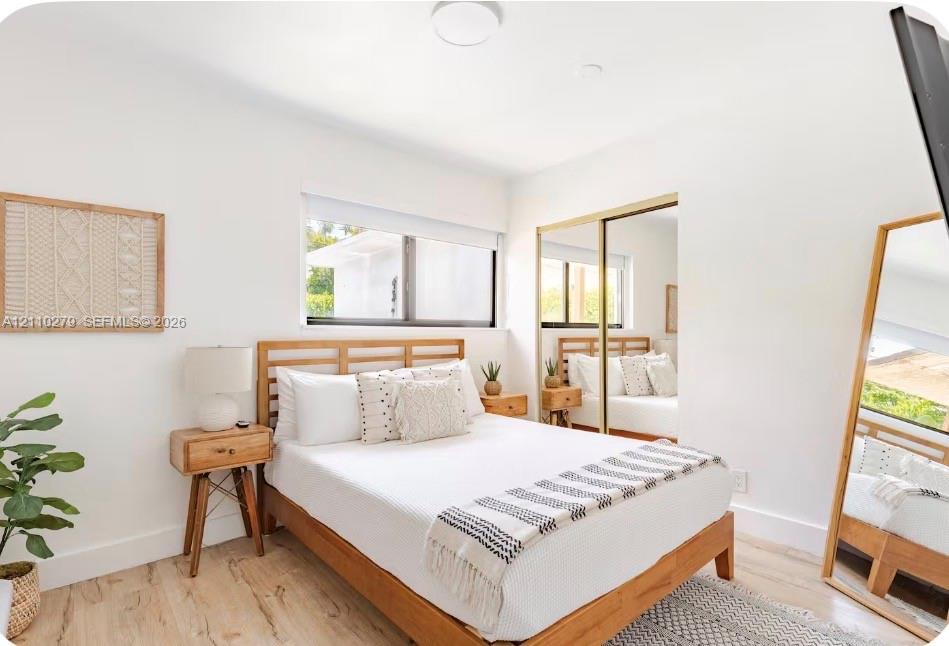 Bright room featuring wood-finish flooring, a horizontal window, and floor-to-ceiling mirrored closet doors