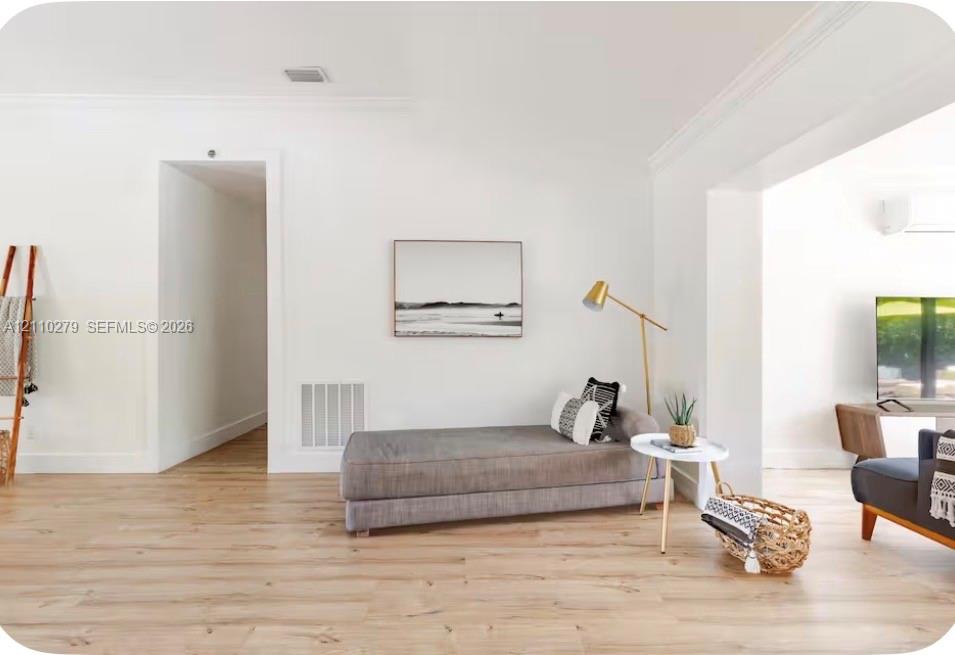 Light-toned wood-finish flooring, crisp white walls, and decorative crown molding