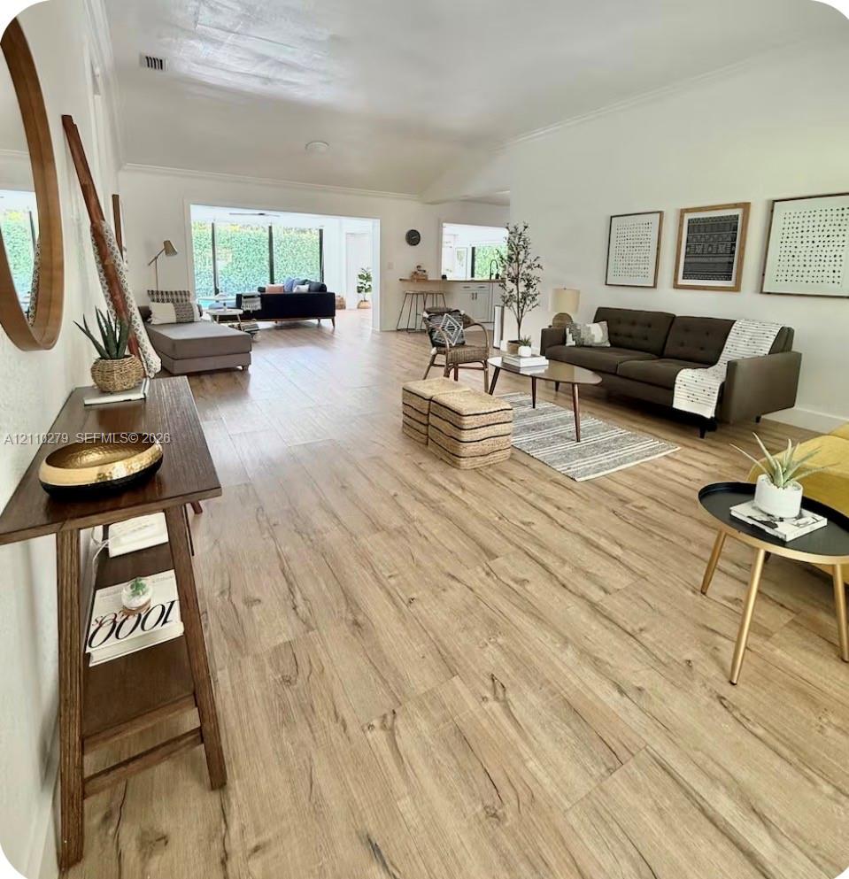 Open-concept interior featuring wood-finish flooring, vaulted ceilings, and floor-to-ceiling glass wall panels
