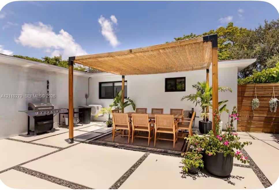 Outdoor patio featuring a custom wood-post pergola with a woven shade canopy, large-format concrete pavers with crushed stone borders, and horizontal wood-slat privacy fencing