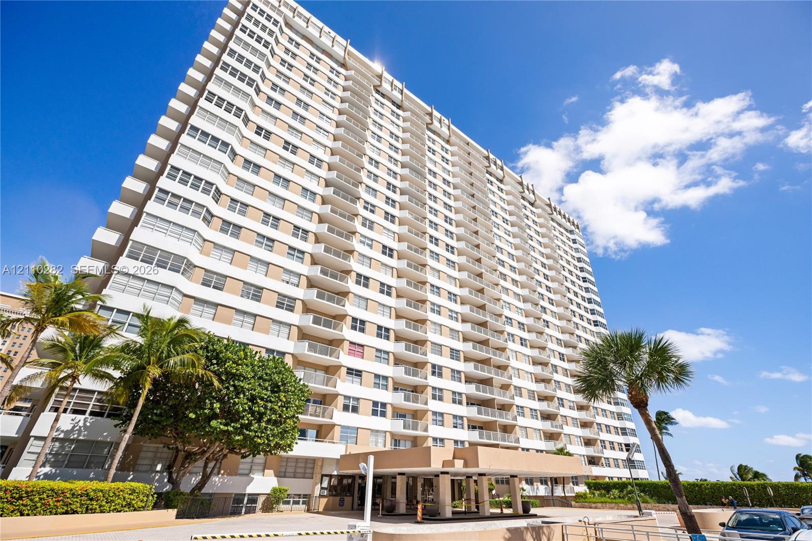 High-rise residential exterior featuring a multi-story facade, integrated private balconies, and a covered porte-cochre entry High-rise residential exterior featuring a multi-story facade, integrated private balconies, and a covered porte-cochre entry