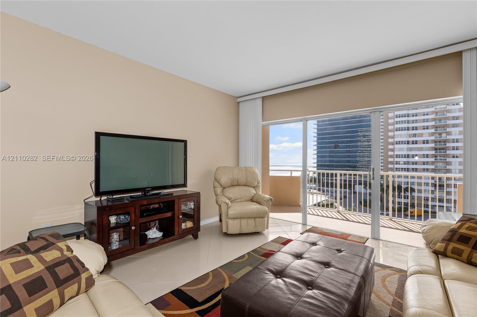 Expansive glass sliding doors featuring vertical blinds, ceramic tile flooring, and access to a private balcony with metal railing