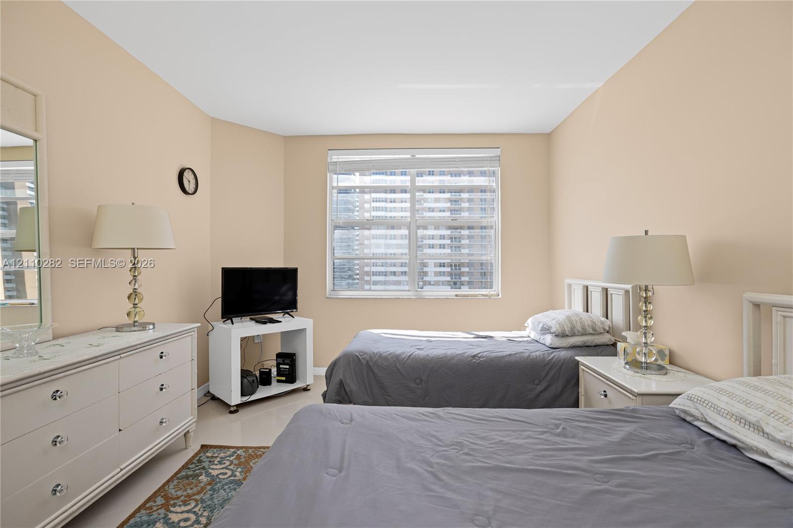 Neutral-toned interior space featuring a large window with horizontal blinds and polished tile flooring