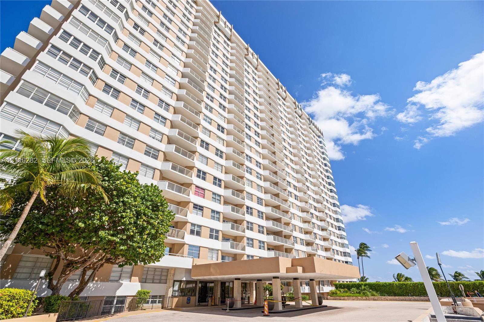 High-rise building exterior featuring a covered porte-cochre, multi-level private balconies, and concrete facade