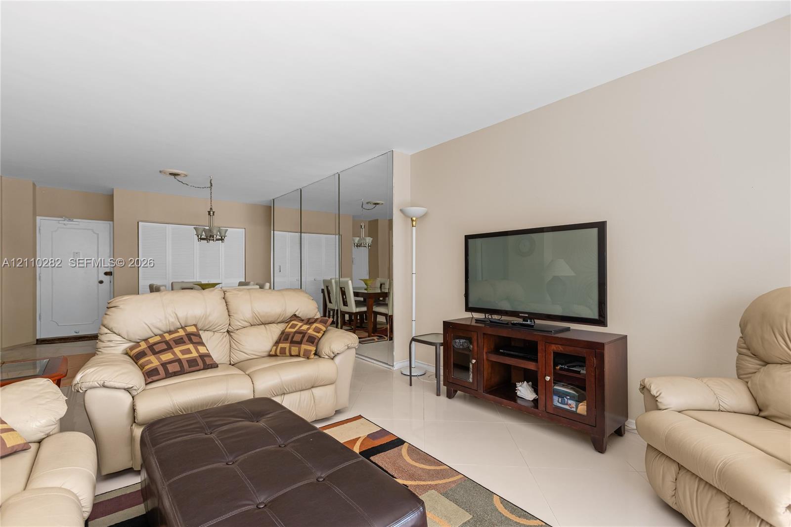 Expansive mirrored wall, neutral-toned flooring, and decorative multi-arm chandelier