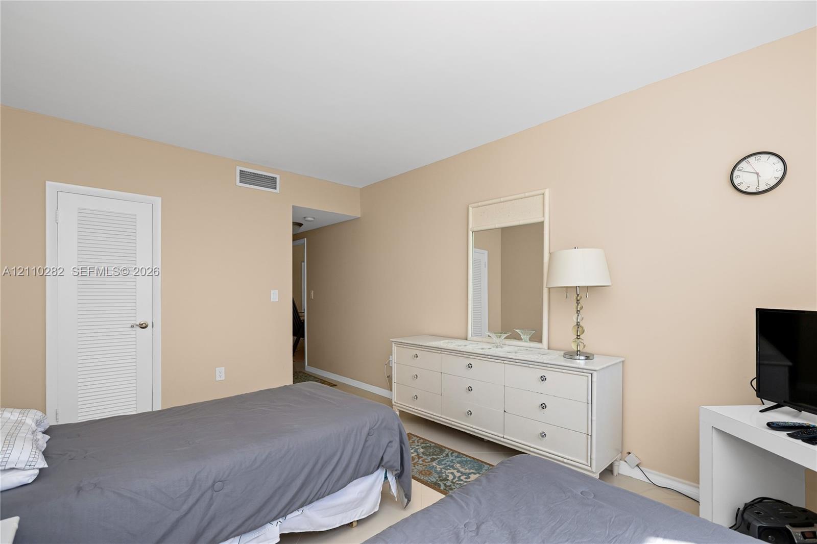Neutral-toned interior space featuring a louvered-panel closet door and solid surface flooring