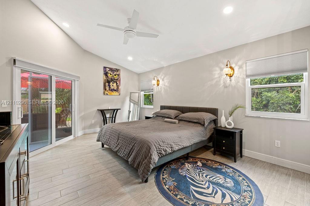 Vaulted ceilings, wood-finish tile flooring, recessed lighting, wall-mounted light fixtures, and glass sliding doors