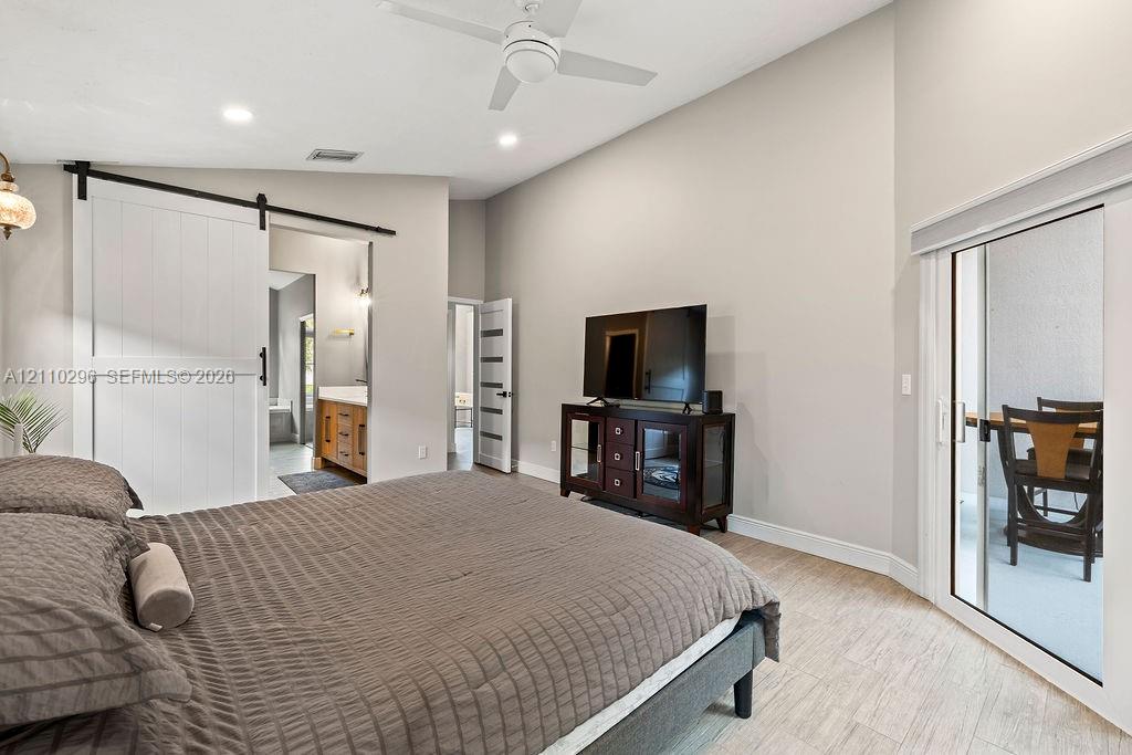 Vaulted ceilings, sliding barn door, neutral interior paint, tile flooring, and glass sliding door
