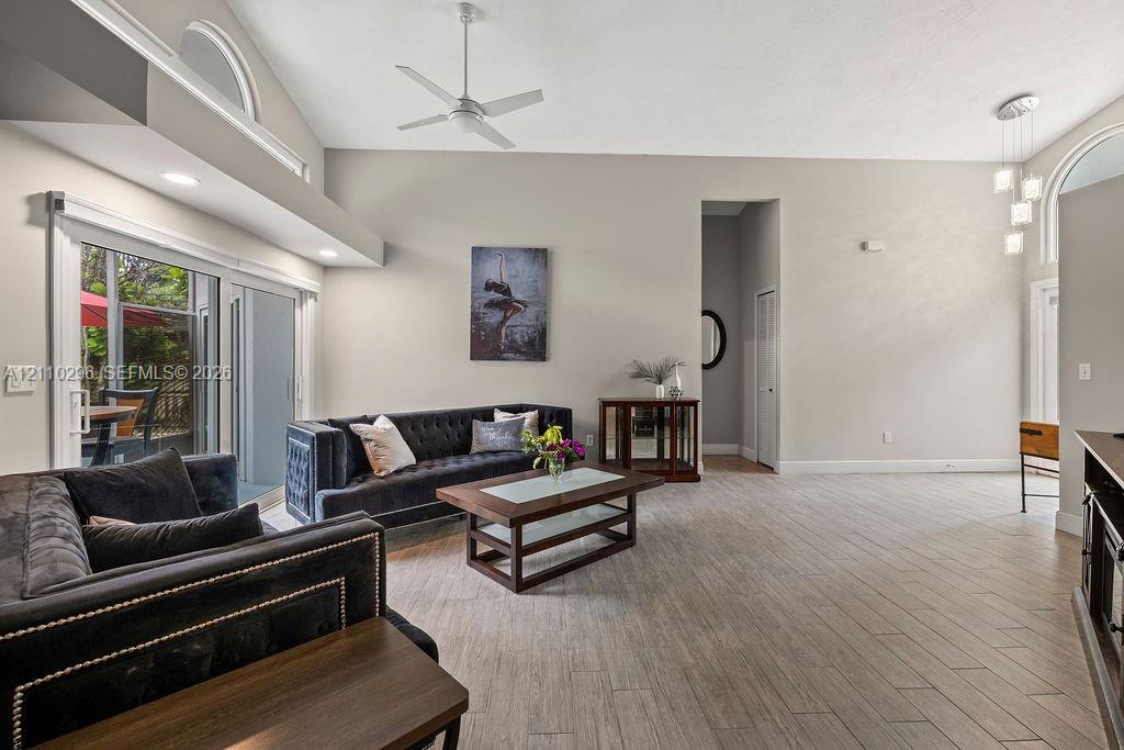 Vaulted ceilings featuring recessed lighting, ceramic wood-finish flooring, sliding glass doors, arched clerestory windows, and modern pendant lighting
