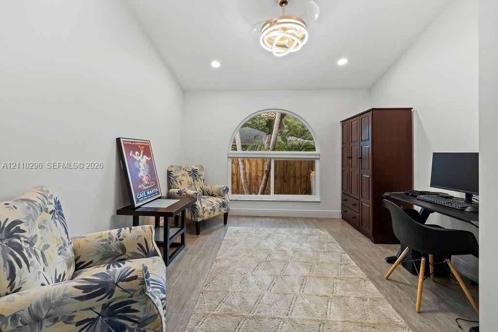 Arched window with decorative trim, wood-finish flooring, recessed lighting, and sculptural tiered ceiling fixture