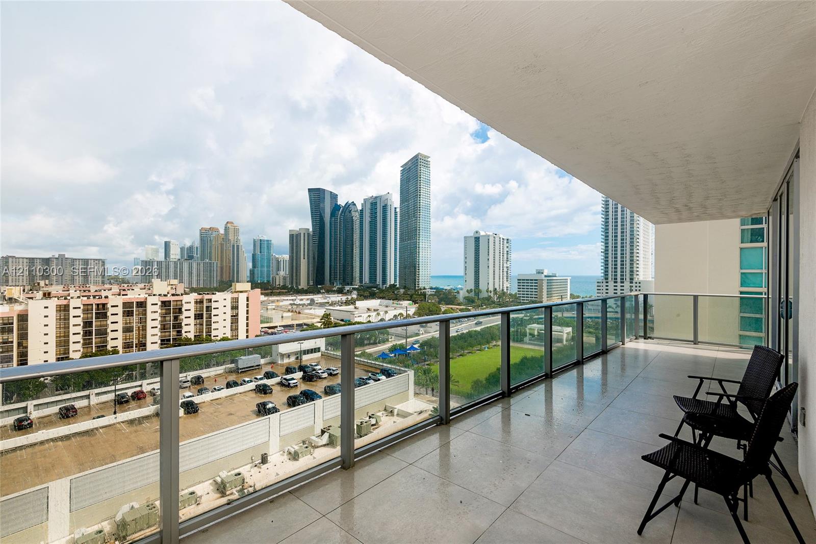 Covered balcony featuring large-format tile flooring and a glass-paneled railing