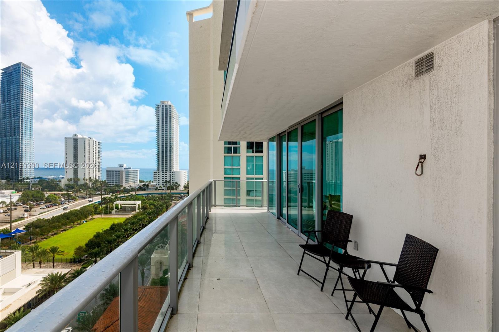 Covered balcony with large-format tile flooring, glass railing system, and floor-to-ceiling sliding glass doors
