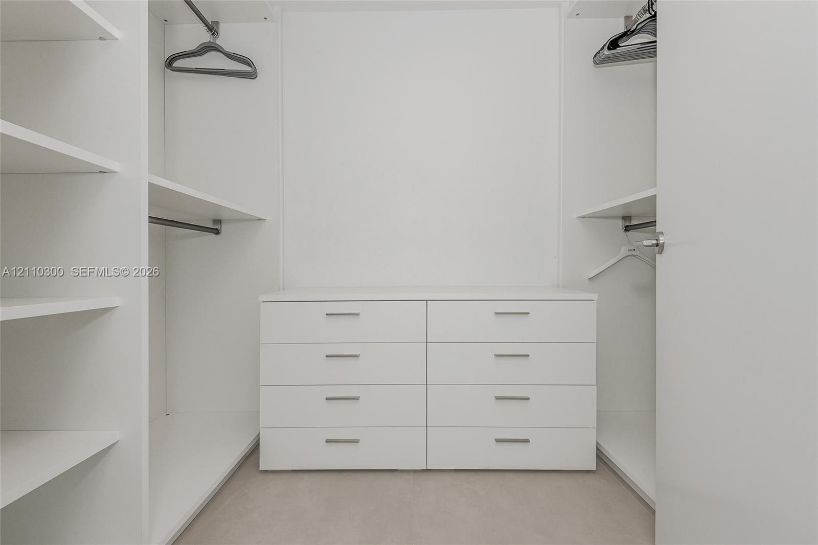 Master Bedroom. Built-in closet featuring white cabinetry, eight integrated storage drawers, adjustable shelving units, and dual metal hanging rods