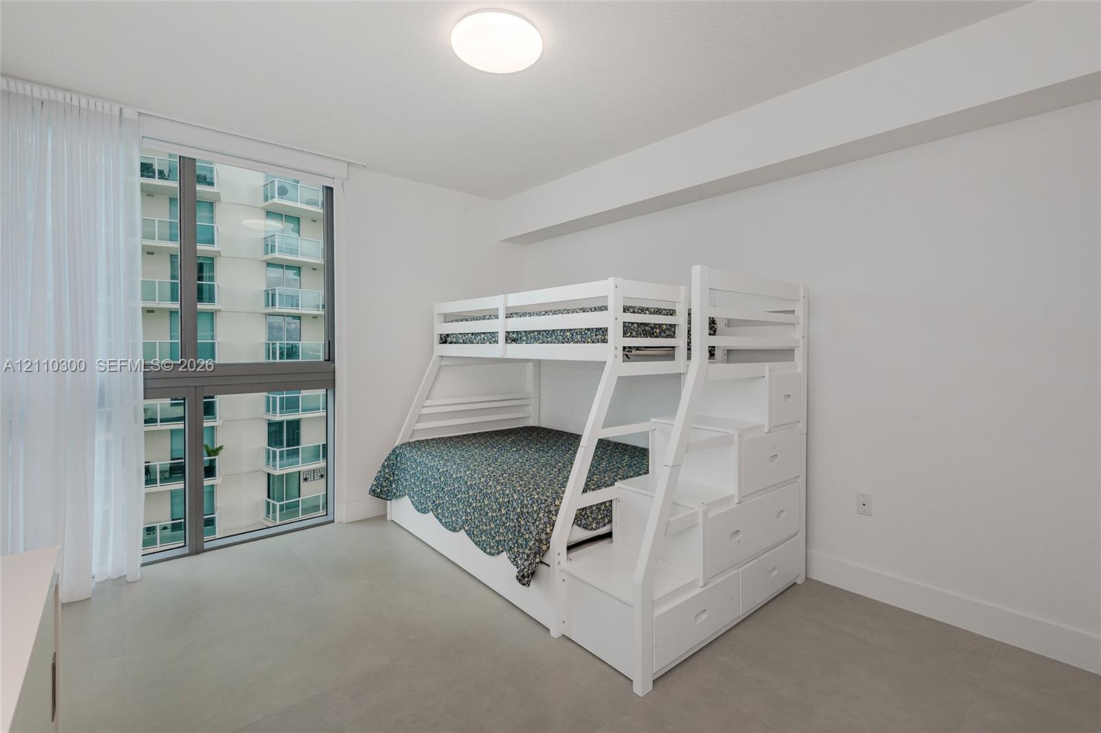Bedroom 3. Floor-to-ceiling windows featuring metal framing, flush-mount overhead lighting, and neutral-tone flooring