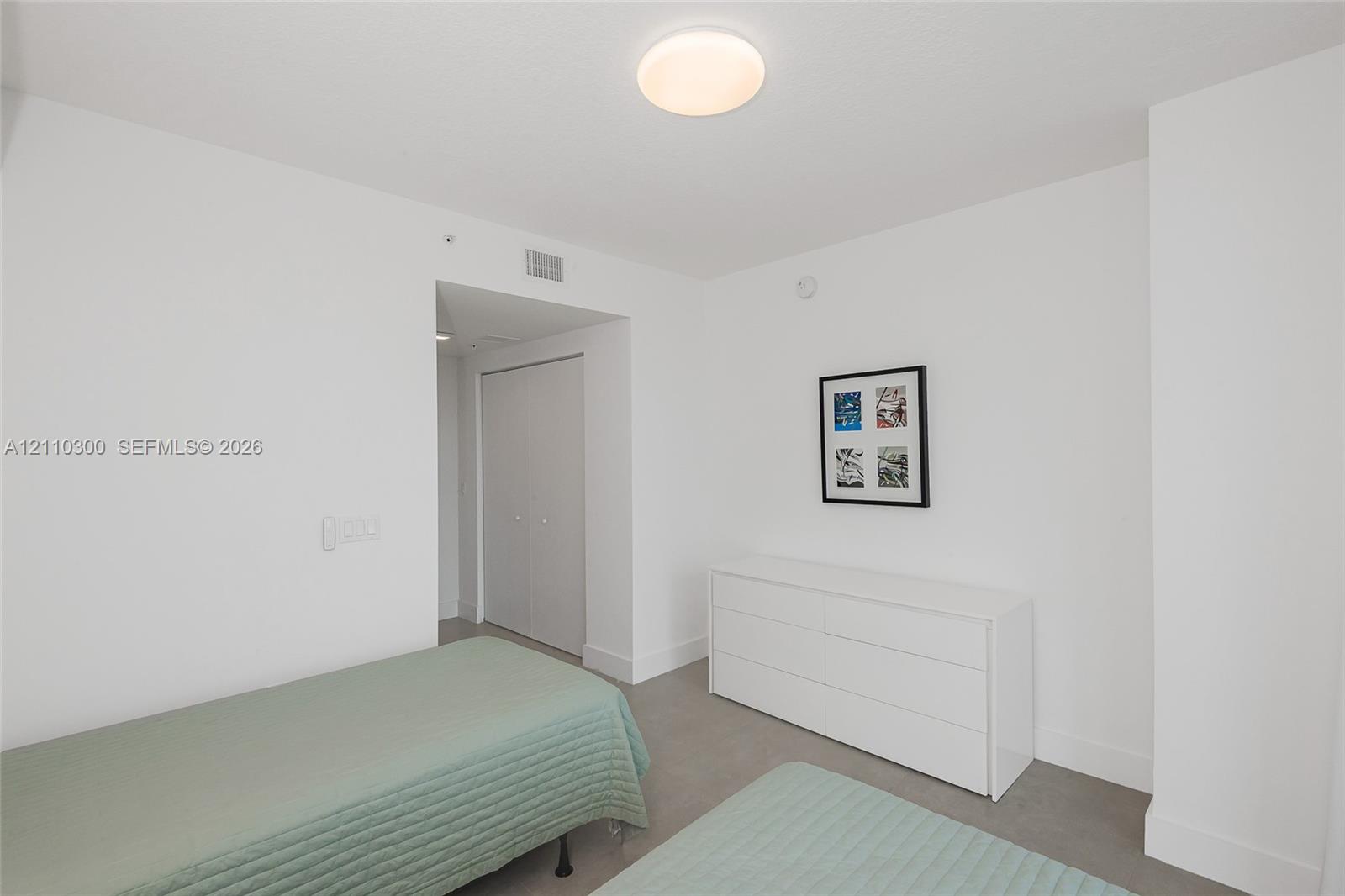 Bedroom 2. Neutral-toned wall-to-wall carpeting, crisp white walls, and a recessed closet with double doors