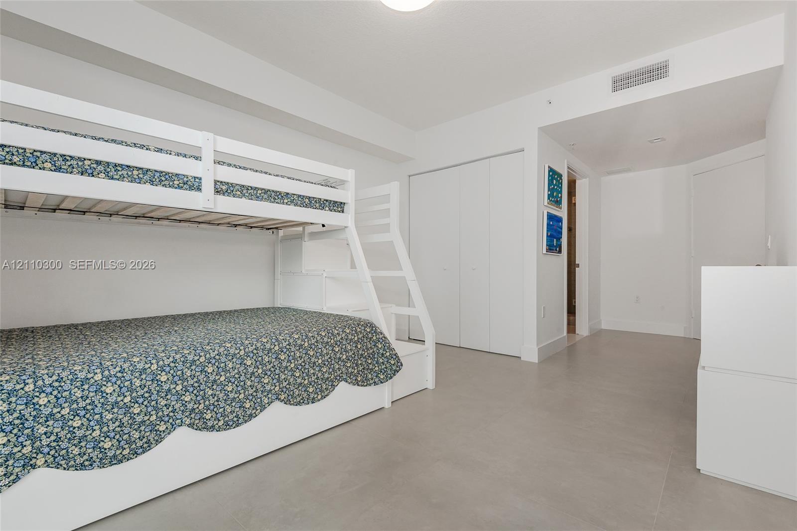 Bedroom 3. Interior space featuring light-toned tile flooring, recessed ceiling lighting, and double-door closet storage