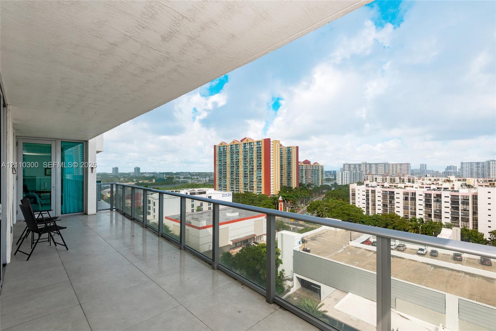 Covered balcony with large-format tile flooring and a glass-paneled railing
