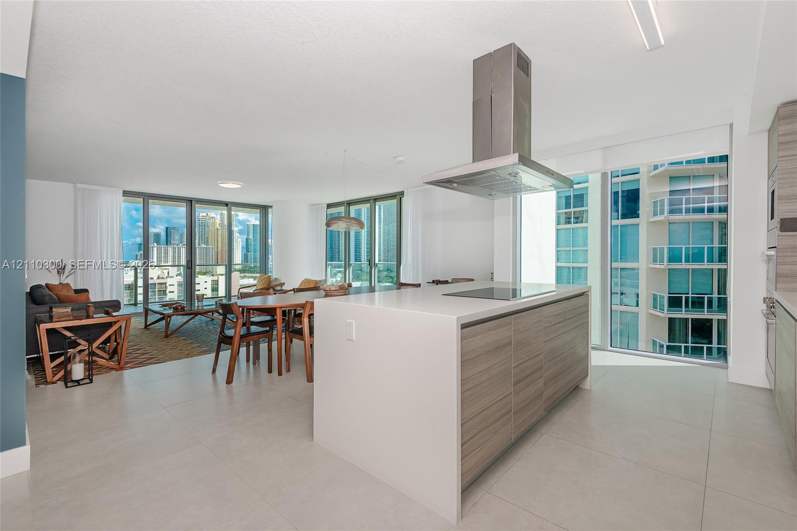 Kitchen featuring a central island with a stone-finish countertop, wood-finish cabinetry, a stainless steel range hood, and tile flooring throughout