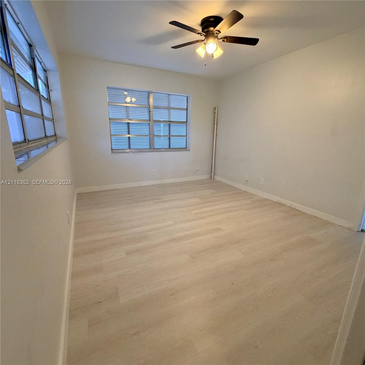 Light-toned wood-finish flooring, multi-pane casement windows, and a ceiling fan with integrated lighting