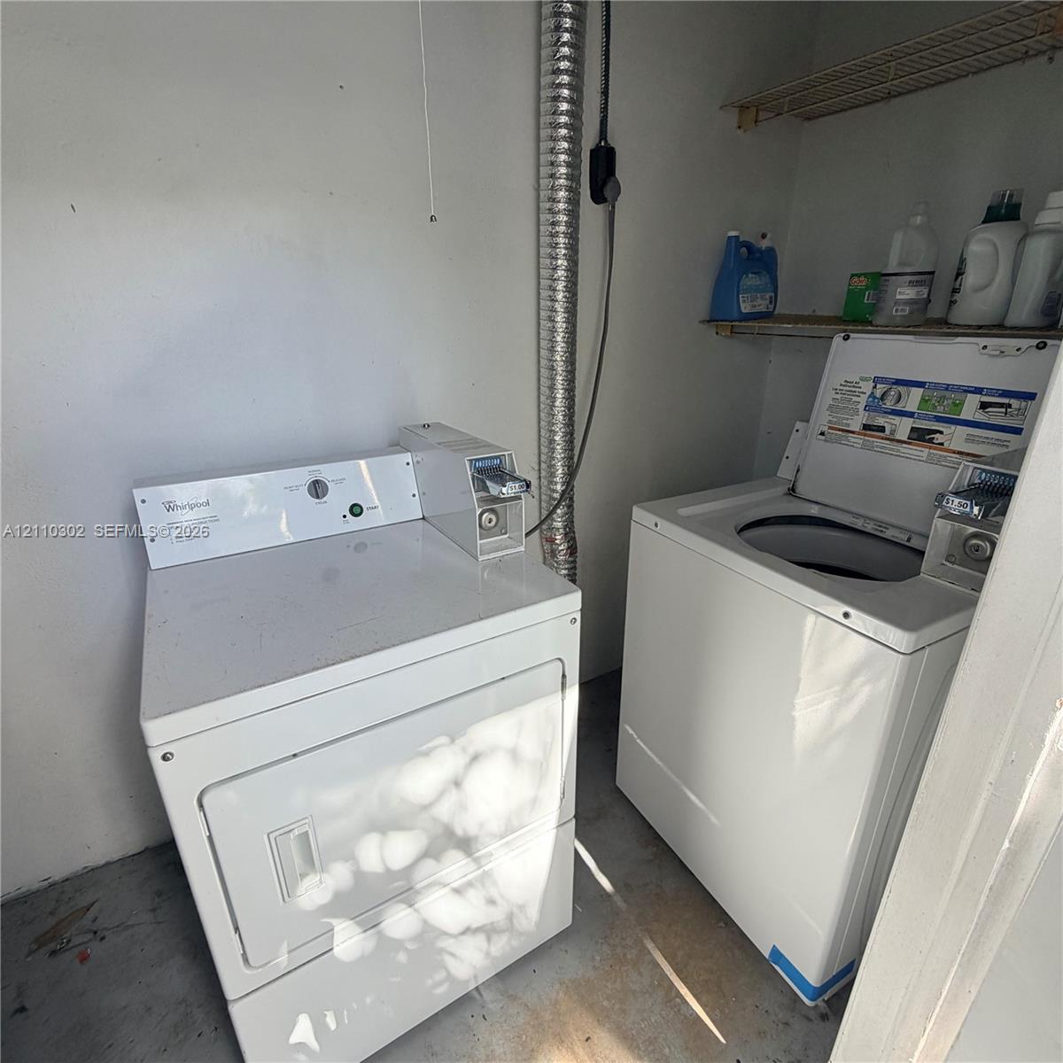 Laundry area featuring coin-operated top-load washer and dryer with wire shelving