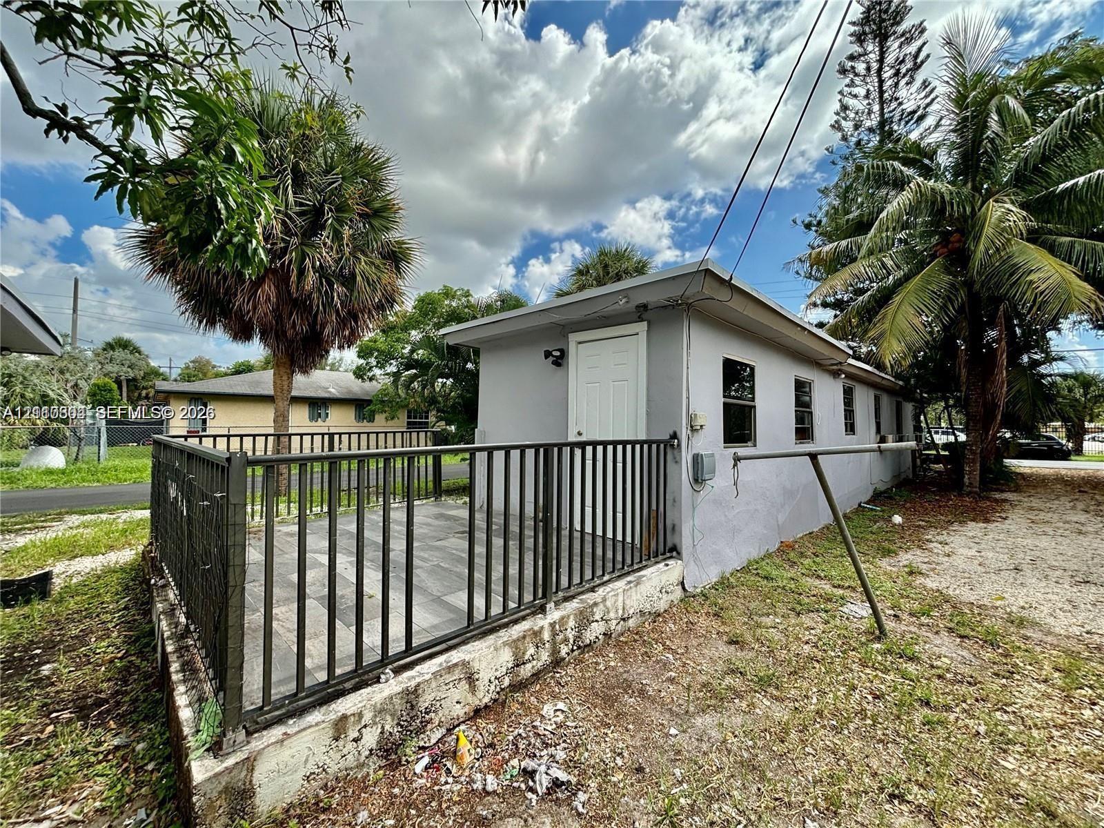 Detached structure featuring a tiled patio, black metal perimeter fencing, and concrete foundation