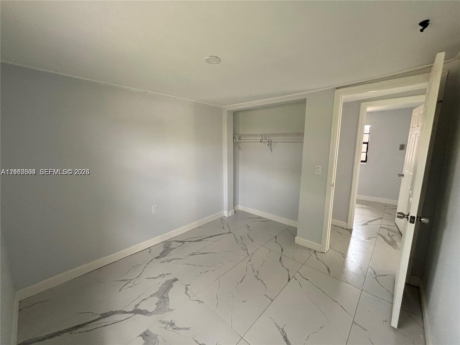 Interior room featuring large-format tile flooring with a neutral veined pattern, recessed ceiling lighting, and a built-in closet with integrated shelving