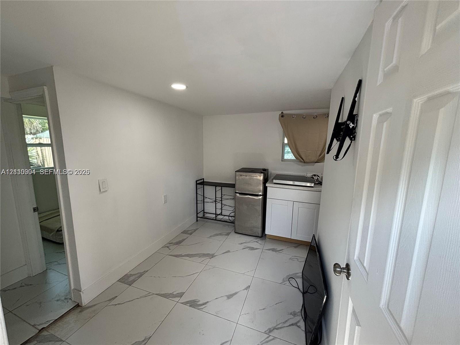 Large-format tile flooring, white shaker-style cabinetry, and recessed lighting