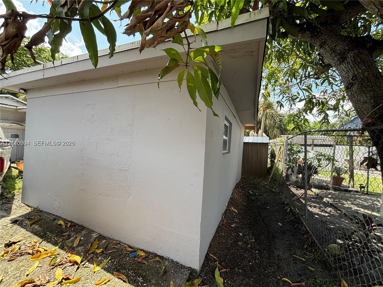 Stucco exterior with a pitched roofline and chain-link fencing