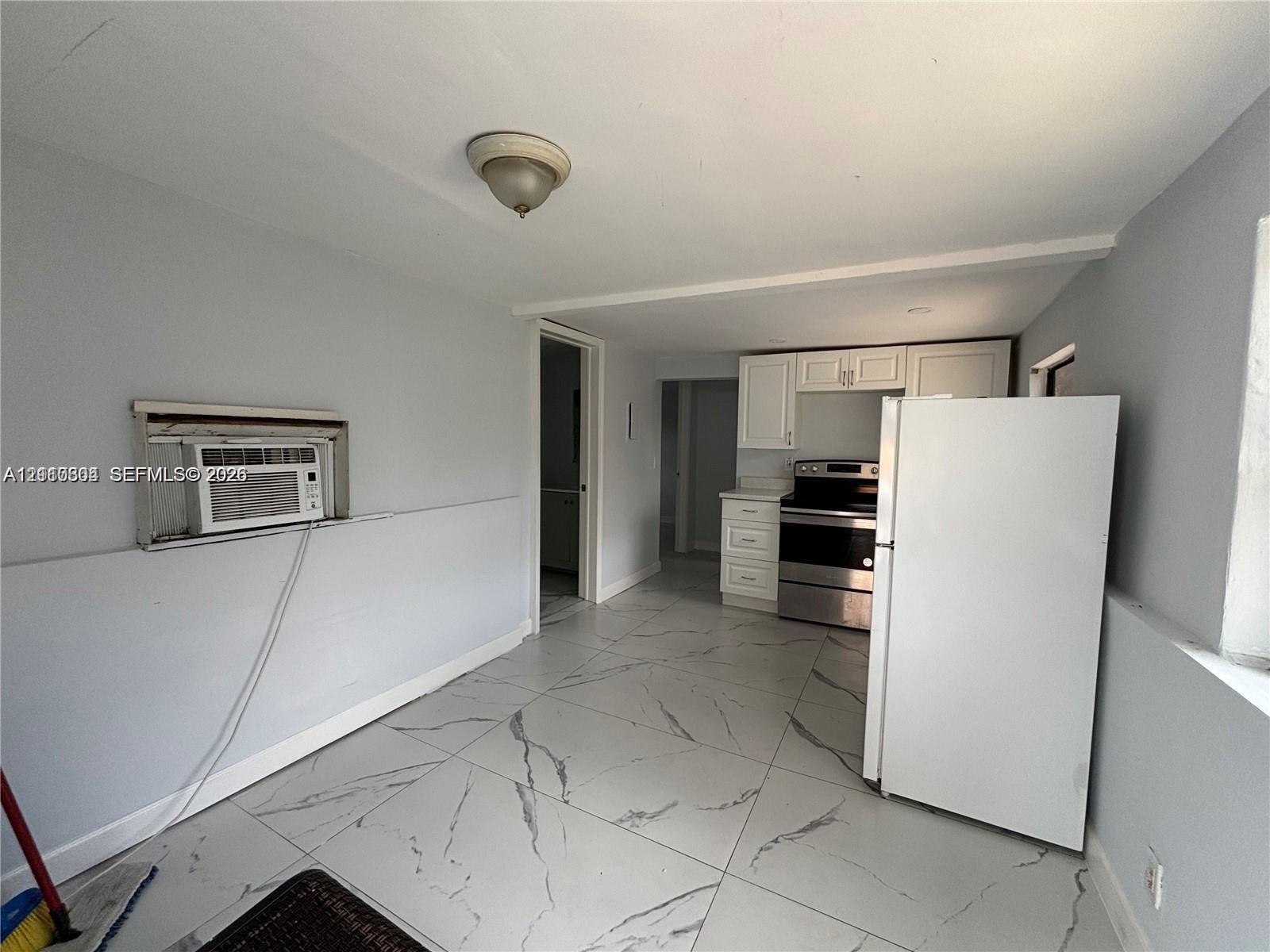 Large-format tile flooring, white cabinetry, and stainless-steel appliances