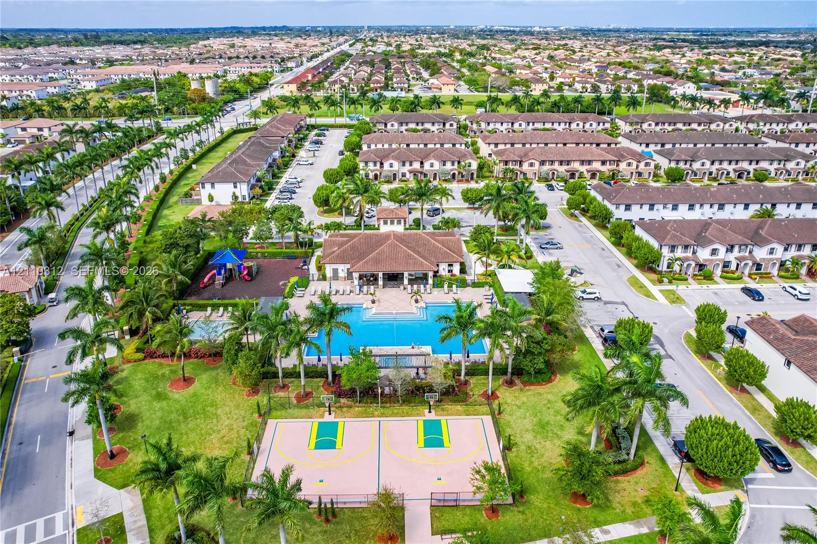 Community clubhouse with an outdoor swimming pool, basketball court, playground, and manicured green spaces