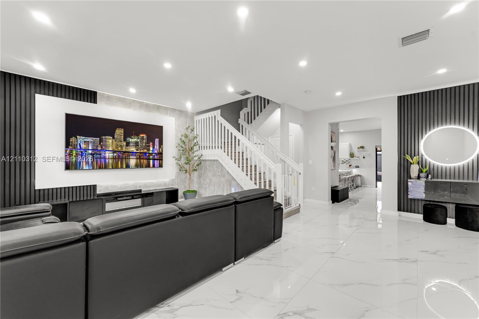 Living area featuring large-format tile flooring, recessed ceiling lighting, vertical slat wall paneling, and a staircase with white wood railings