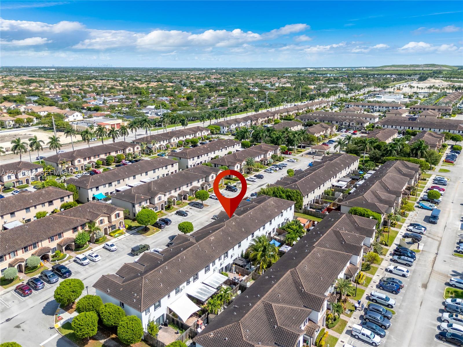 Aerial perspective of a multi-unit residential complex featuring dark-toned tiled roofing, uniform architectural design, and integrated paved parking areas