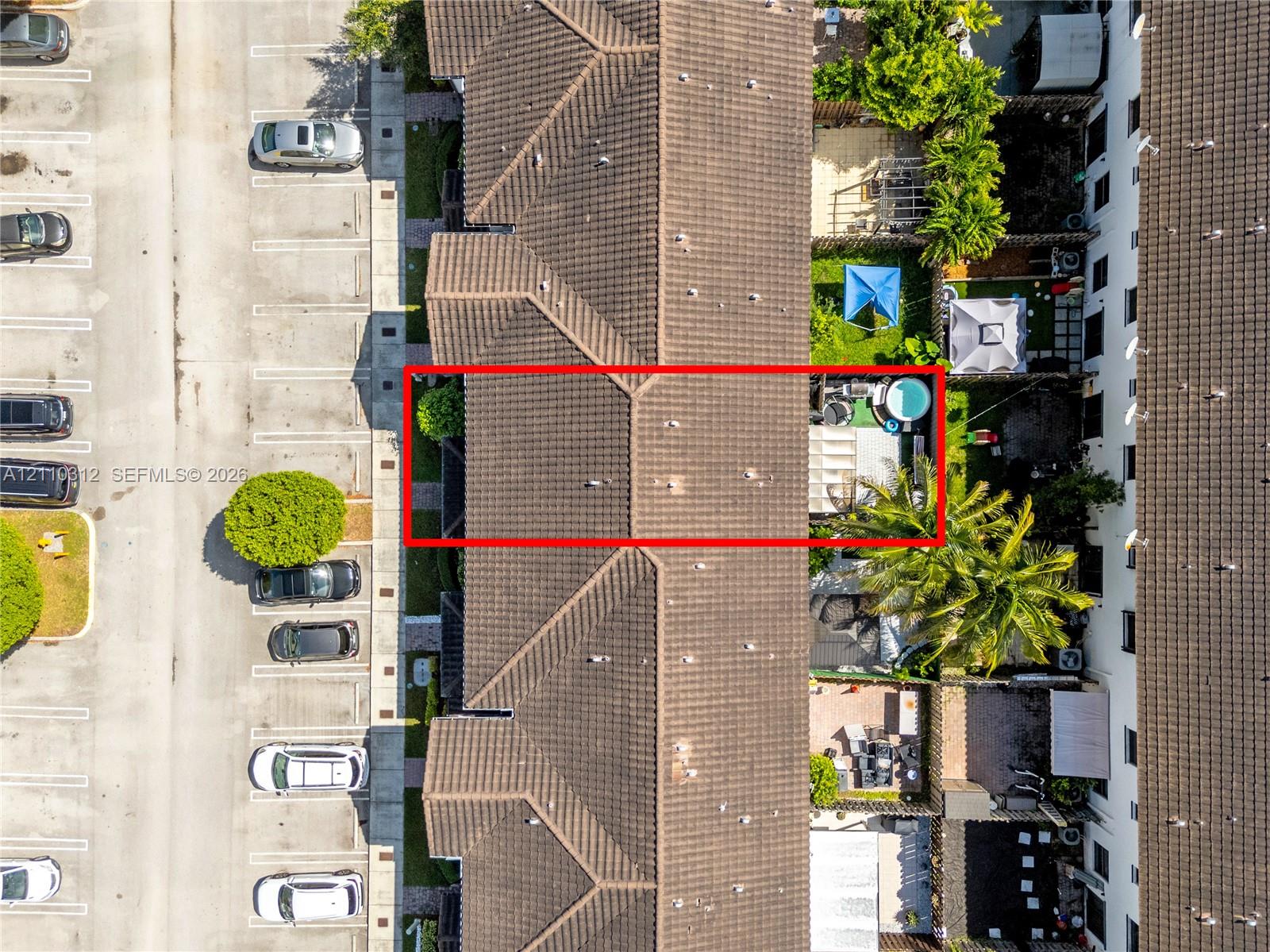 Aerial perspective featuring a tile roof, private enclosed outdoor area, and paved surface