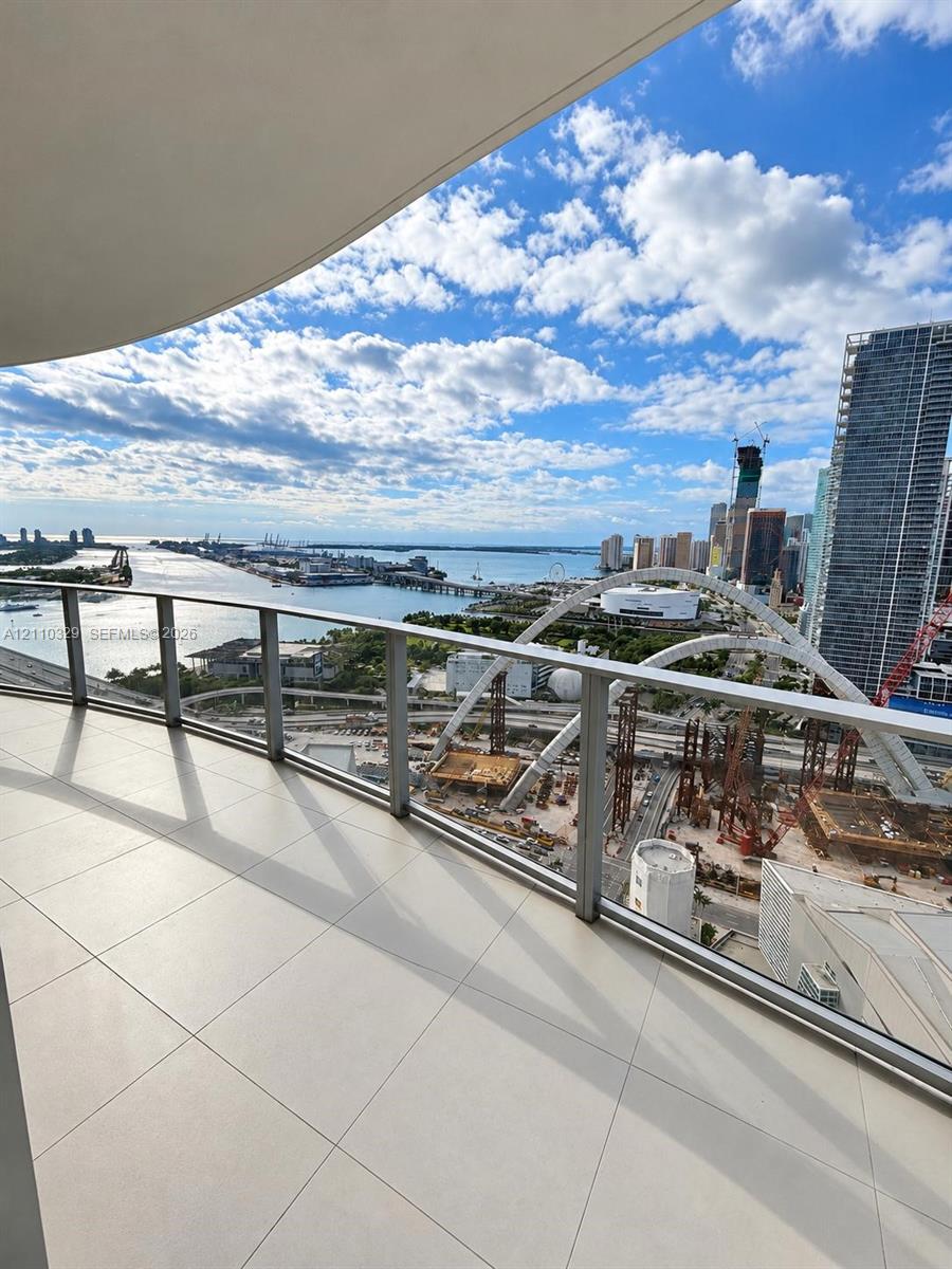 Covered balcony featuring large-format tile flooring and a glass railing system with metal framing