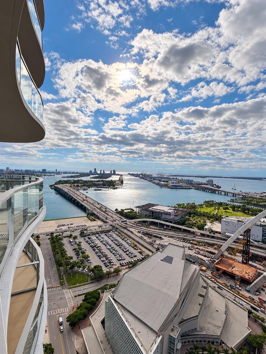 Curved private balcony featuring glass railings and panoramic water and city skyline outlooks