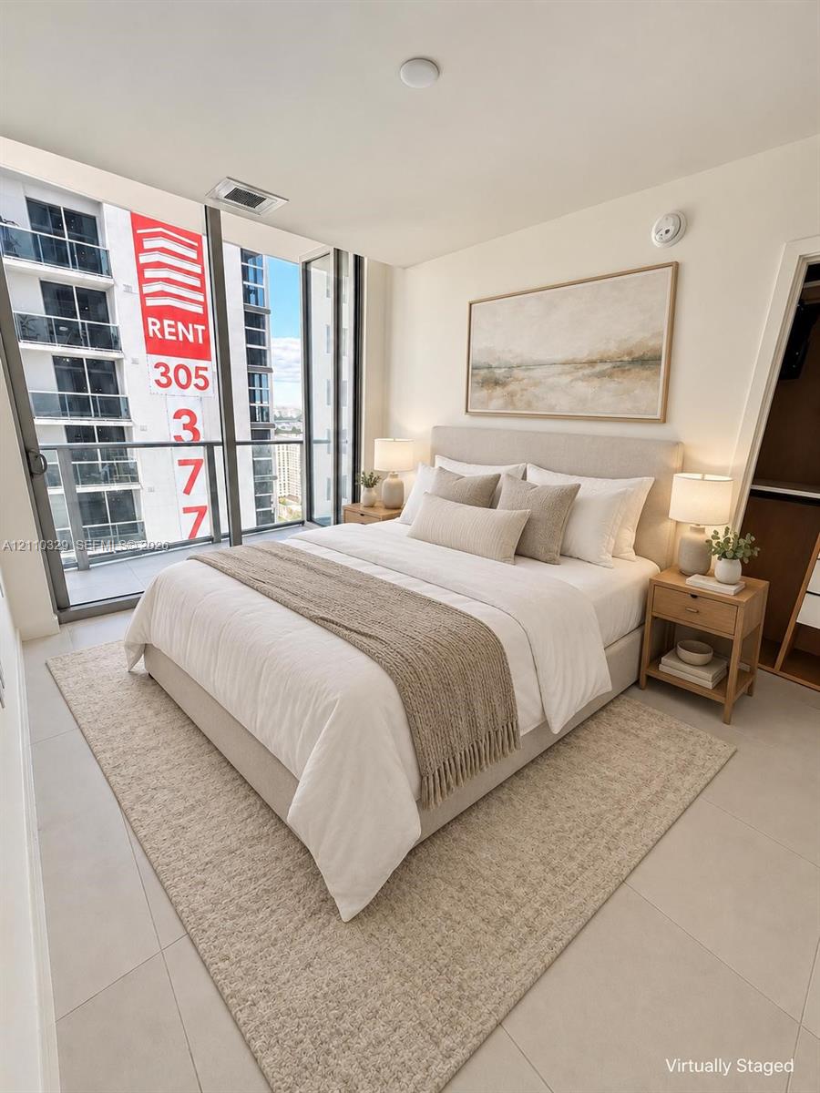 Floor-to-ceiling glass windows, neutral-toned large format tile flooring, and a walk-in closet with built-in shelving