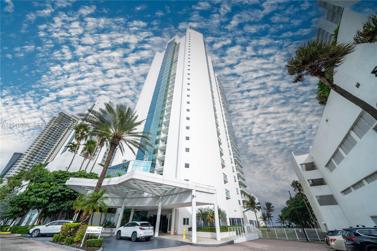 High-rise residential tower featuring a glass-paneled facade, private balconies, and a porte-cochre entry with structural columns