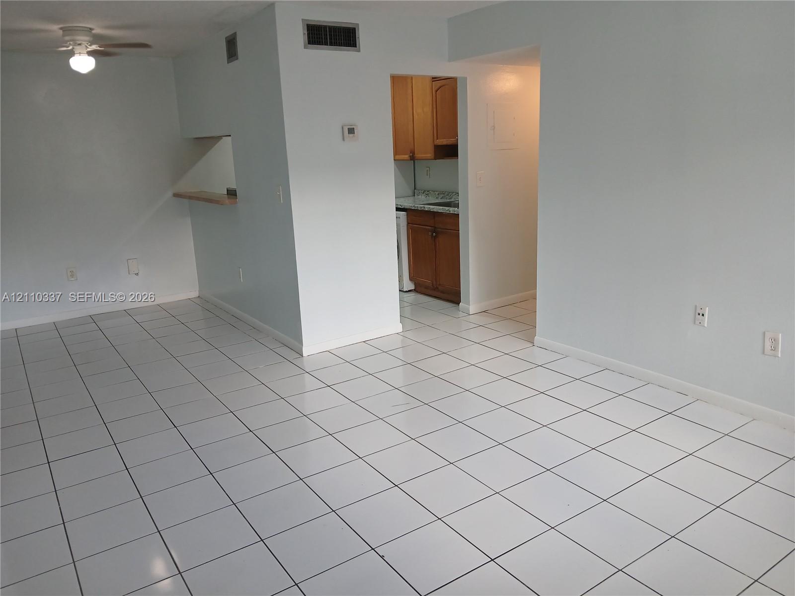 Interior space featuring ceramic tile flooring, a pass-through opening to the kitchen, and a ceiling-mounted light fixture
