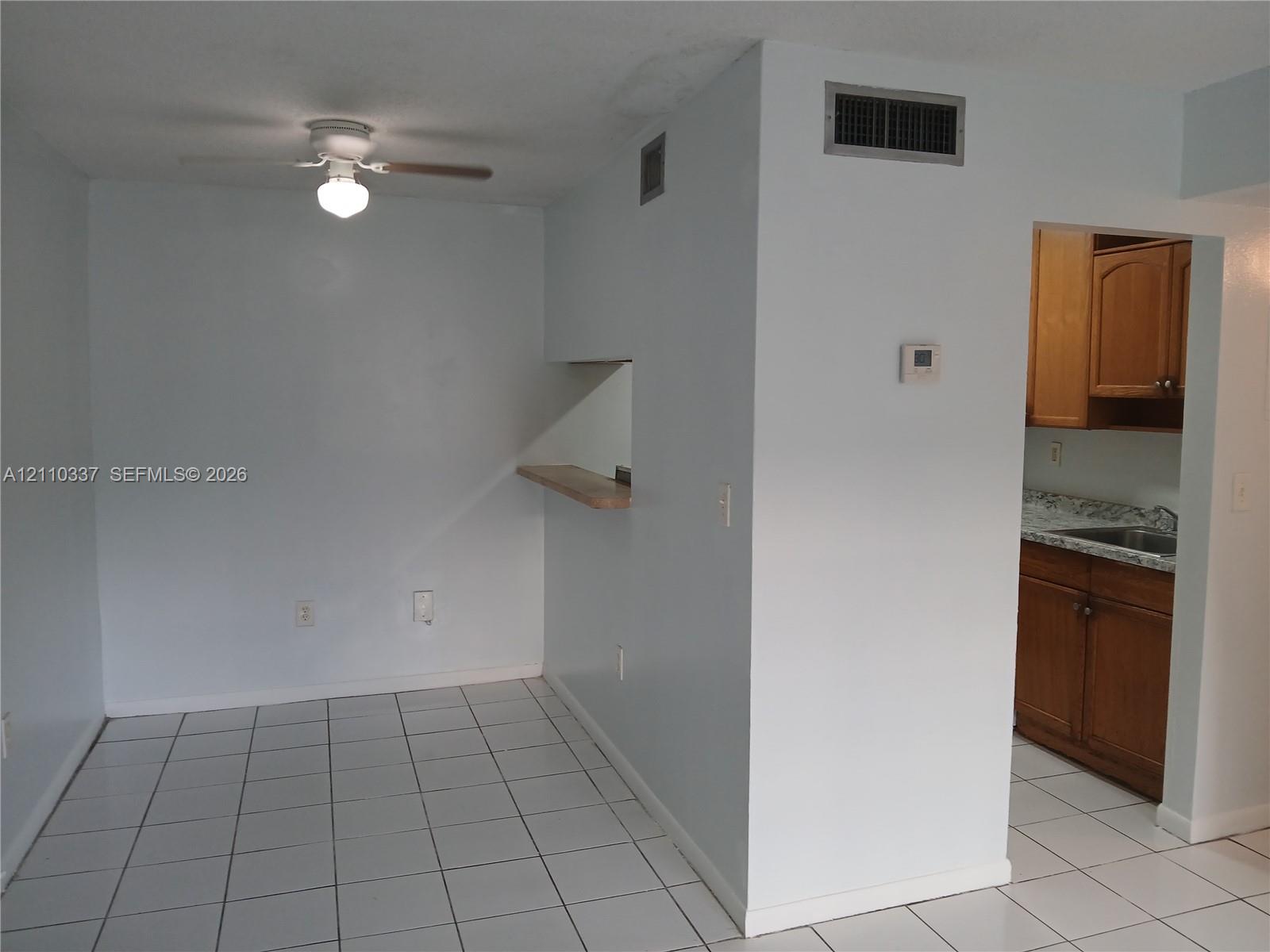 Ceramic tile flooring, white ceiling fan with attached light fixture, and pass-through window with wooden shelf