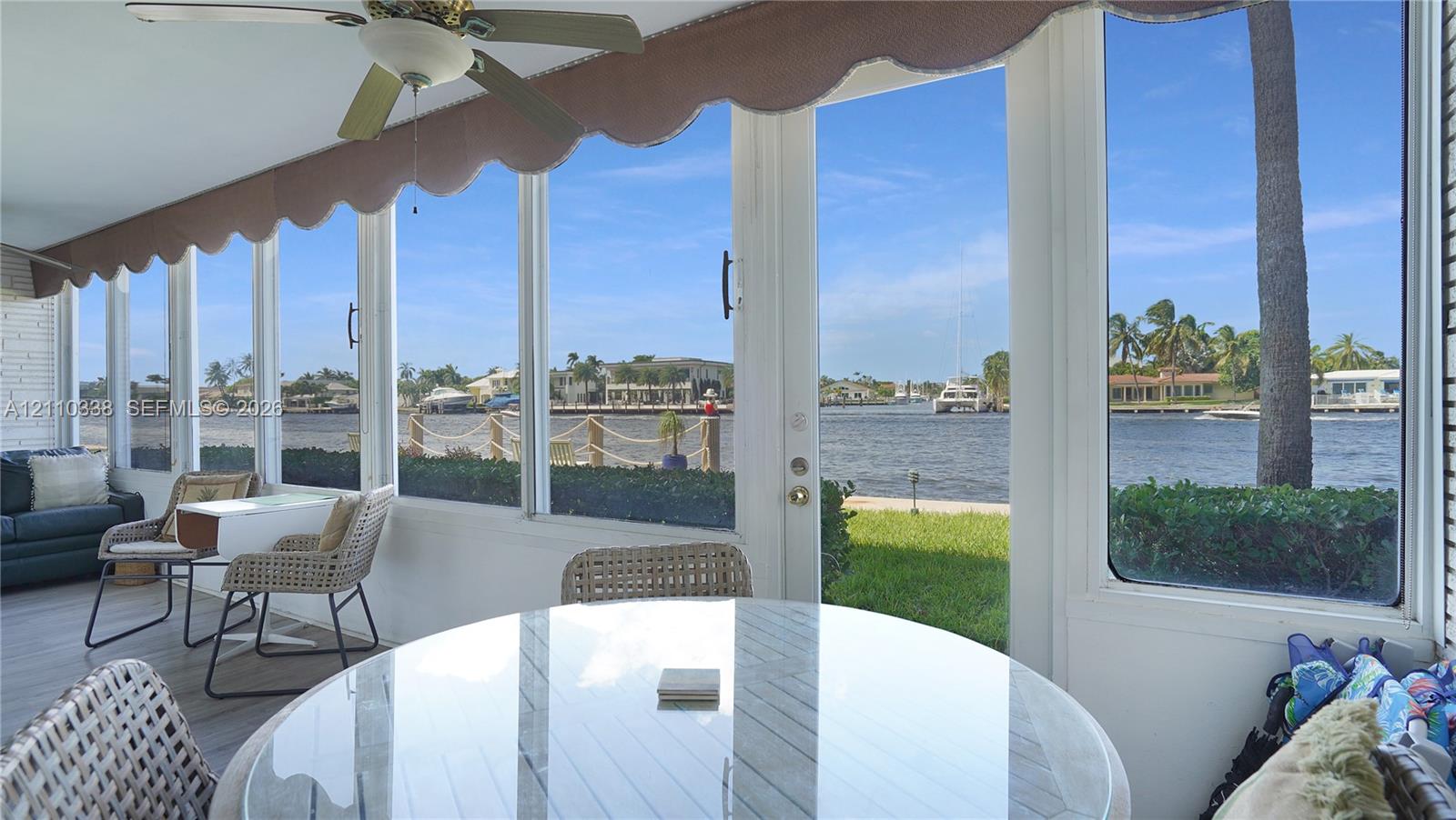 Enclosed porch featuring floor-to-ceiling windows, waterfront exposure, ceiling fan, and painted masonry walls Enclosed porch featuring floor-to-ceiling windows, waterfront exposure, ceiling fan, and painted masonry walls
