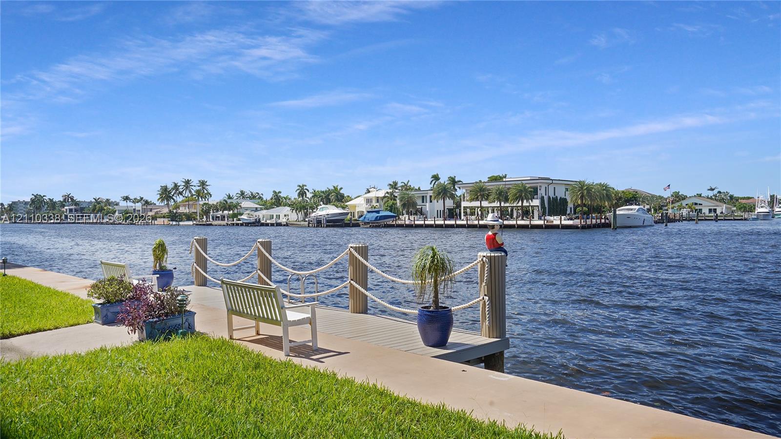 Waterfront property featuring a private dock, concrete bulkhead, manicured lawn, and nautical-style rope railing