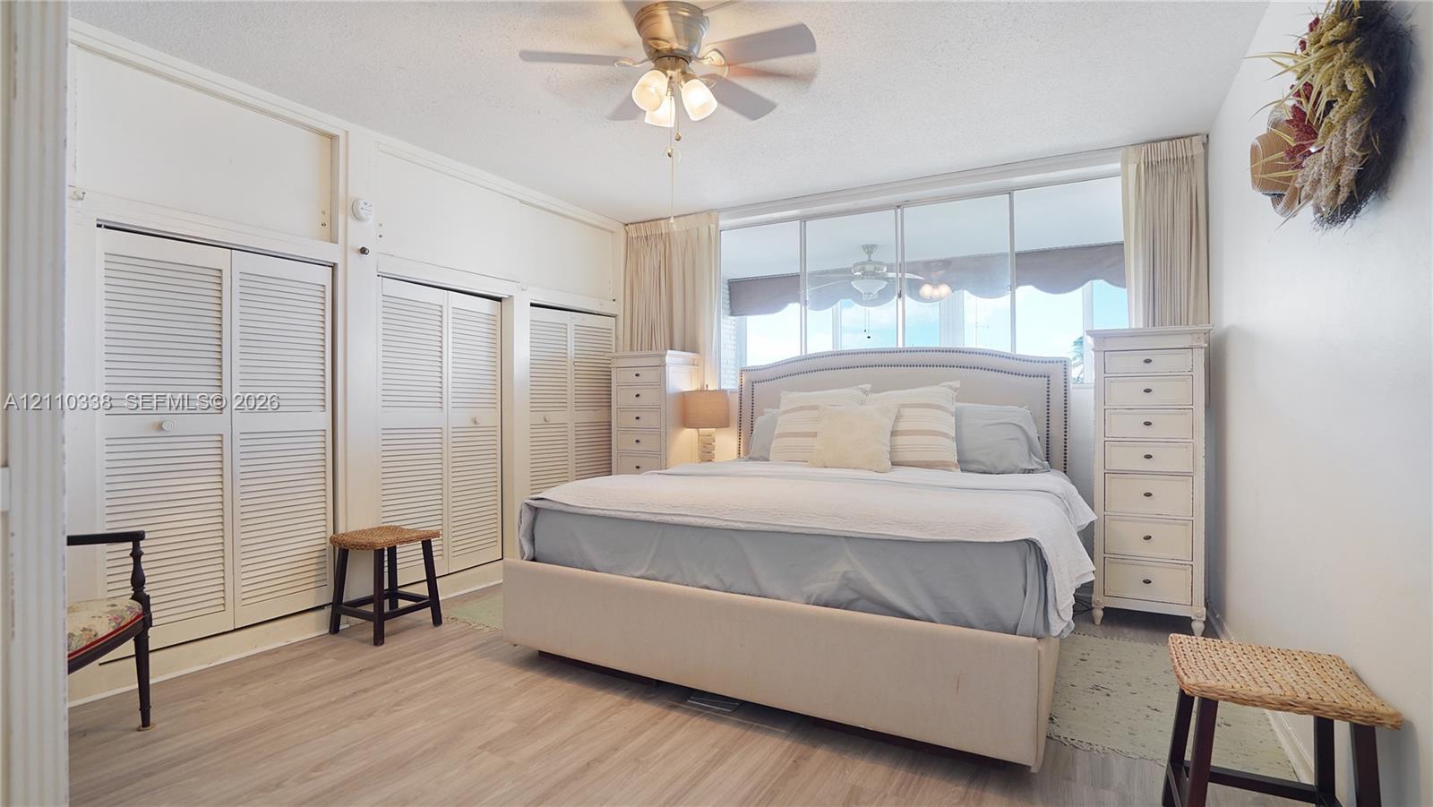 Wood-finish flooring, multi-panel louvered closet doors, ceiling fan with integrated lighting, and expansive wall-to-wall glass windows WATER VIEWS!