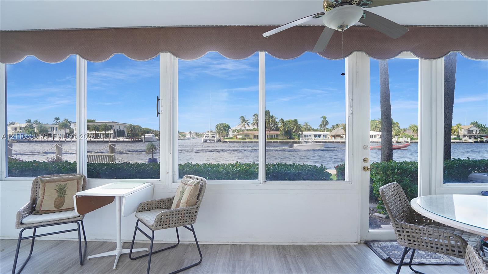 featuring expansive glass windows, wood-finish flooring, and a ceiling-mounted fan featuring expansive glass windows, wood-finish flooring, and a ceiling-mounted fan