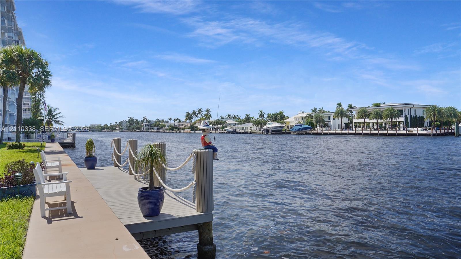 Concrete seawall bulkhead with an extended composite dock, rope railings, and manicured turf grass