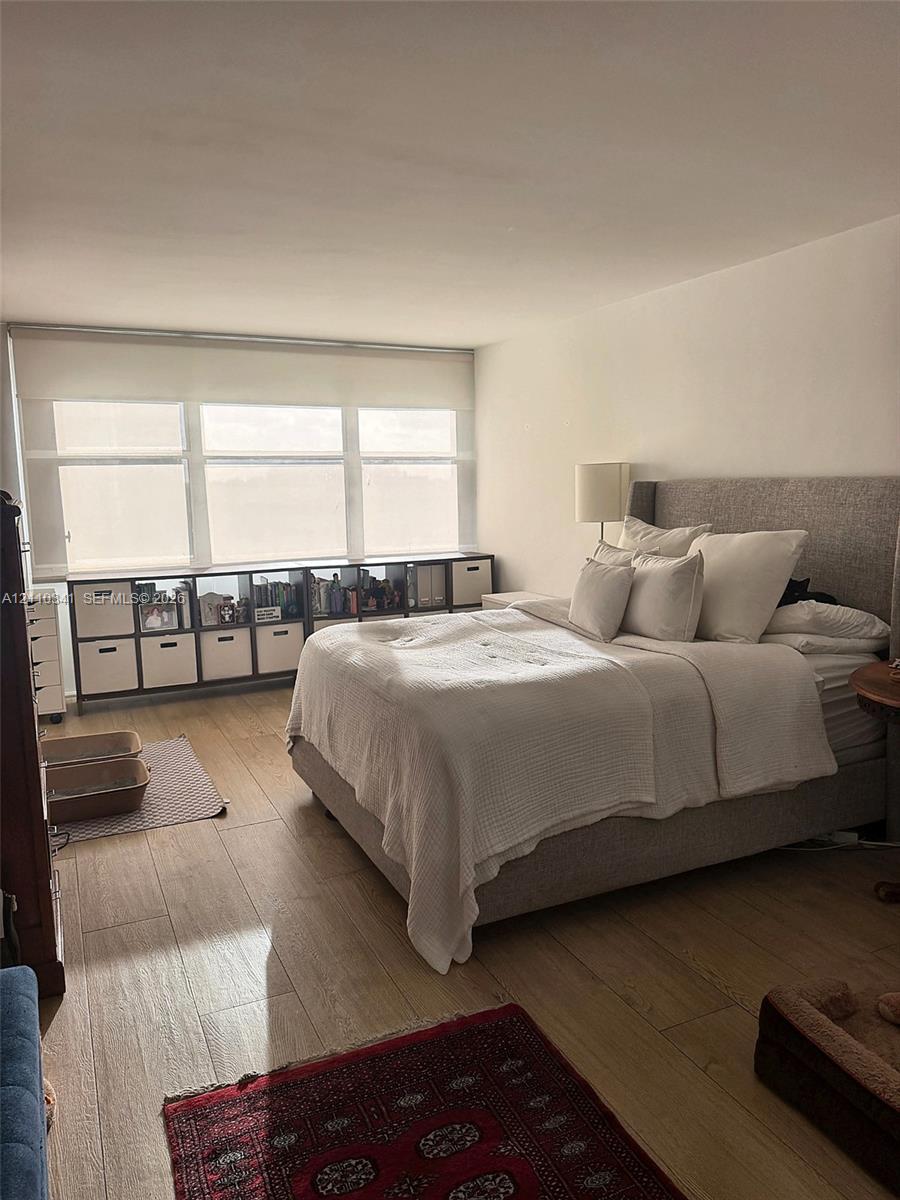 Room featuring wood-finish flooring and a multi-pane window with a neutral roller shade Room featuring wood-finish flooring and a multi-pane window with a neutral roller shade