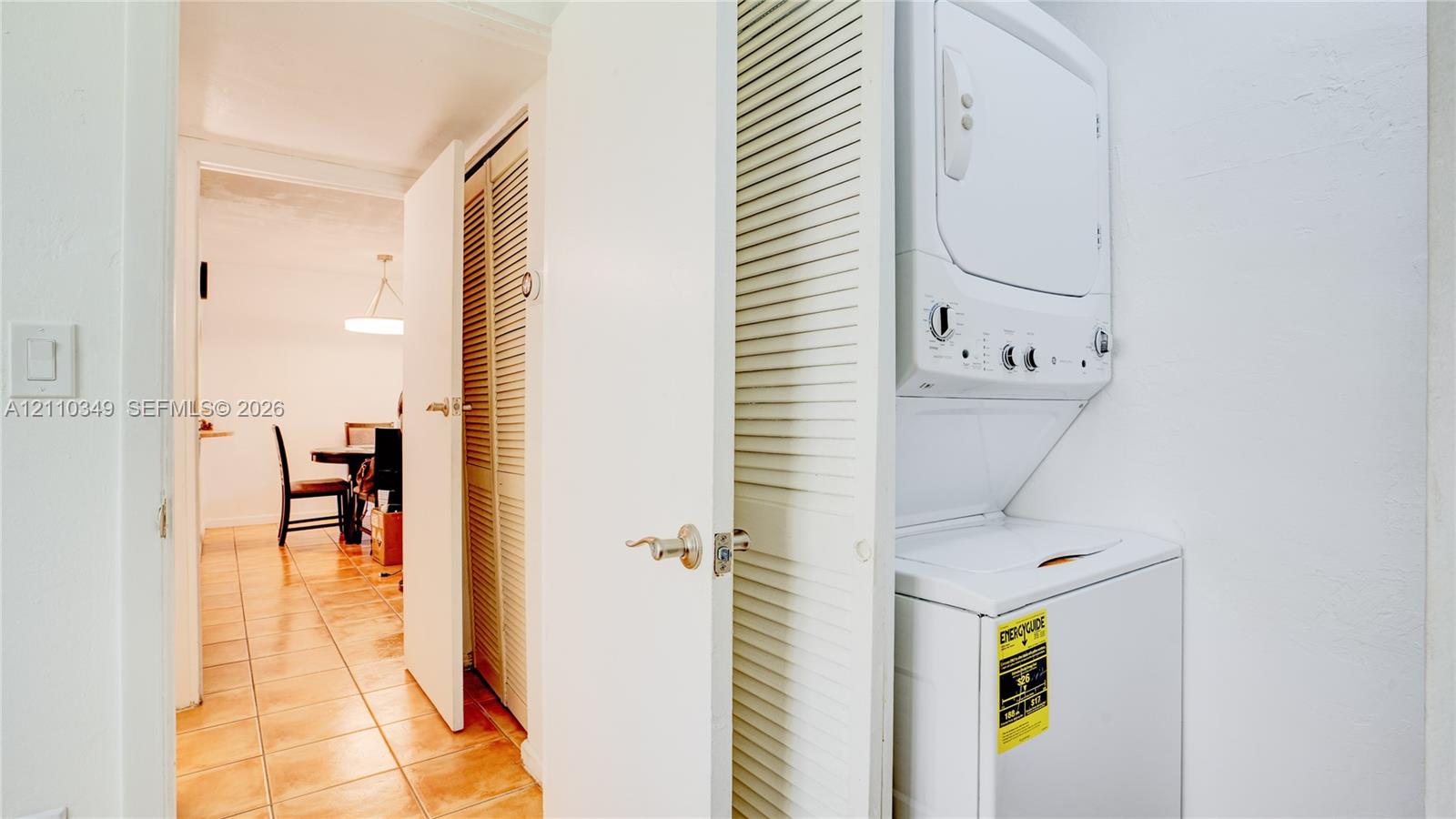 Laundry area featuring a stacked washer and dryer unit and floor-to-ceiling louvered closet doors
