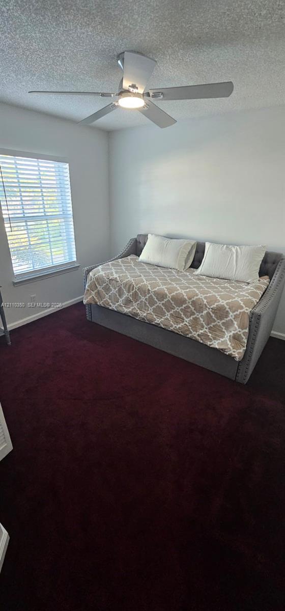 Room featuring deep-toned carpeting, white walls, and a ceiling fan with an integrated light fixture